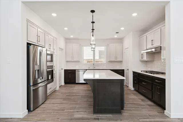 a large kitchen with stainless steel appliances kitchen island granite countertop a stove a refrigerator and a sink