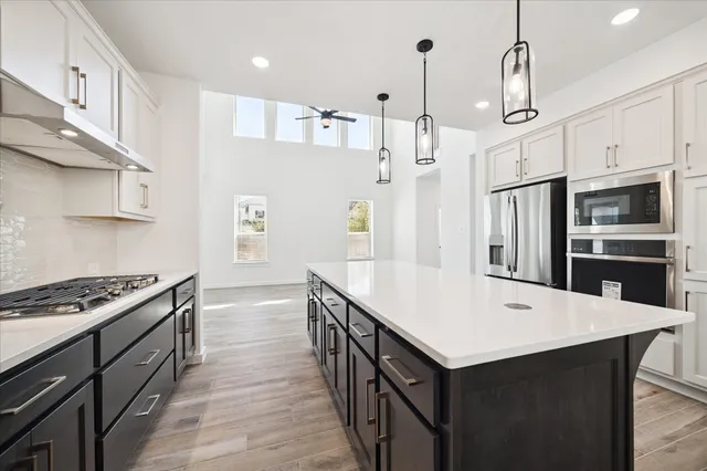 a kitchen with stainless steel appliances a stove a sink a refrigerator and cabinets