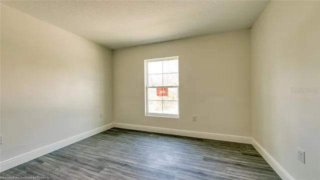an empty room with wooden floor and window