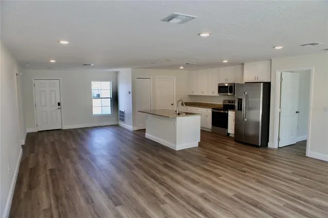 a kitchen with stainless steel appliances a refrigerator and wooden floor