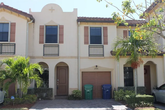 a front view of a house with plants and palm trees