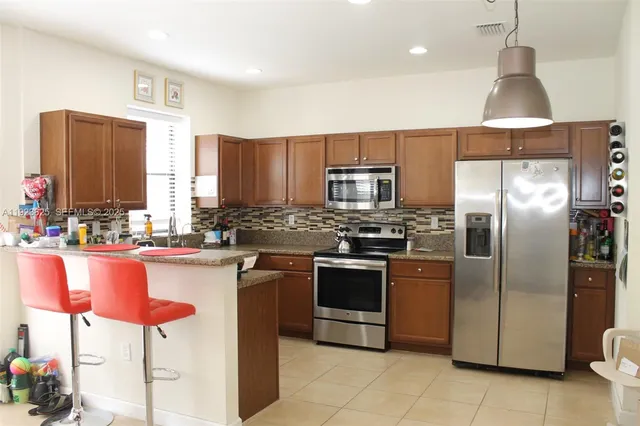 a kitchen with stainless steel appliances granite countertop a sink a stove and a refrigerator