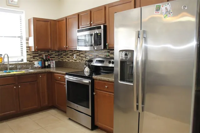 a kitchen with stainless steel appliances granite countertop a refrigerator and a sink
