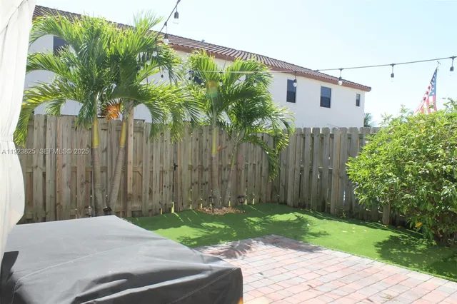 a backyard of a house with plants and trees with wooden fence