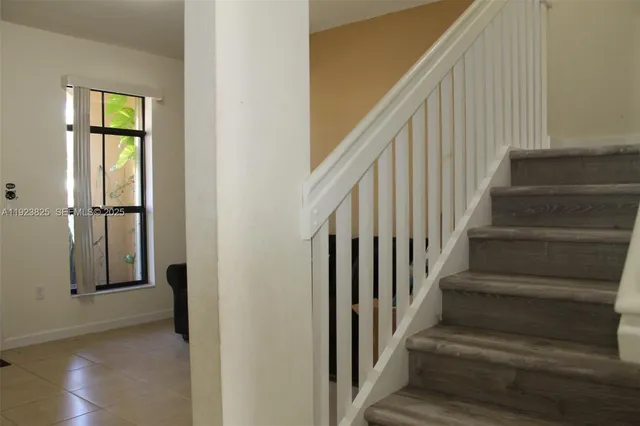 a view of staircase with lots of frames on wall and a window