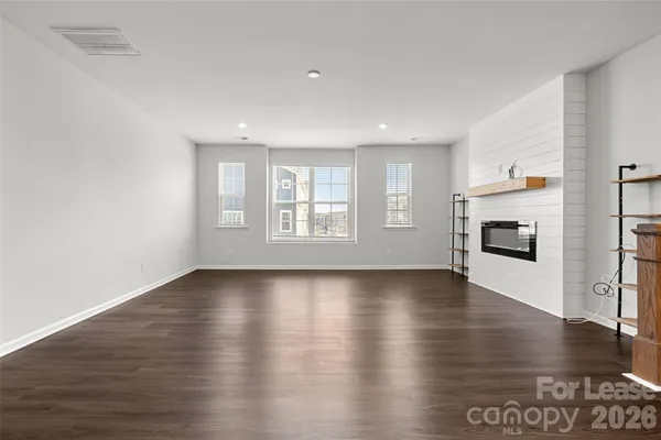 a view of an empty room with window and wooden floor