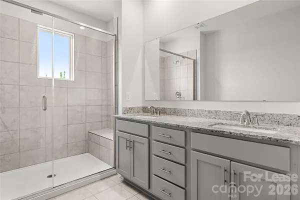 a bathroom with a granite countertop sink a mirror and a shower