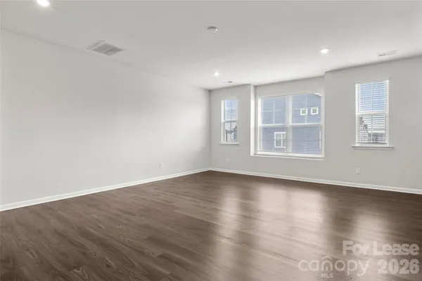 a view of an empty room with wooden floor and windows