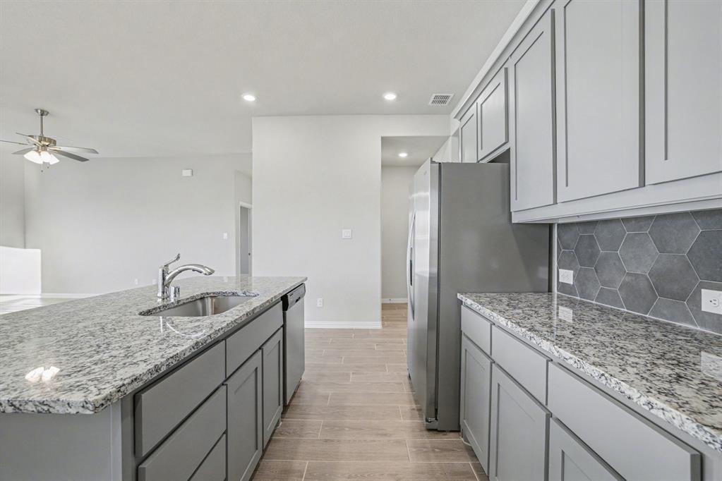 2404 Peebles Lane Denton, TX 76207 - Photo 11 of 30 a kitchen with granite countertop a sink and cabinets