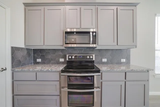 a kitchen with granite countertop white cabinets and stainless steel appliances
