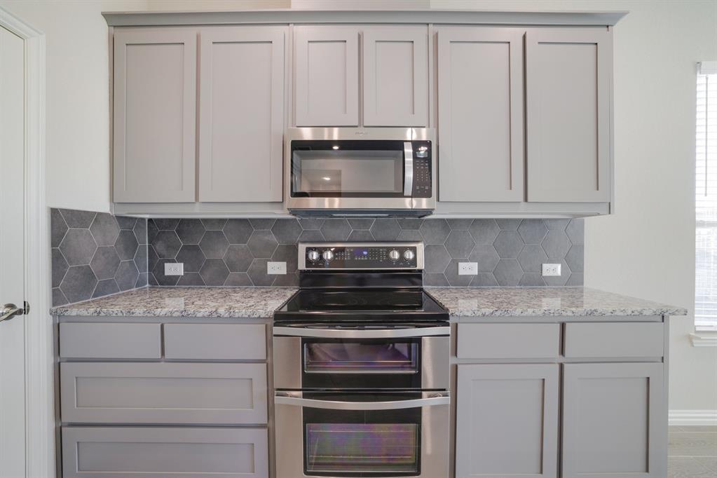 2404 Peebles Lane Denton, TX 76207 - Photo 12 of 30 a kitchen with granite countertop white cabinets and stainless steel appliances