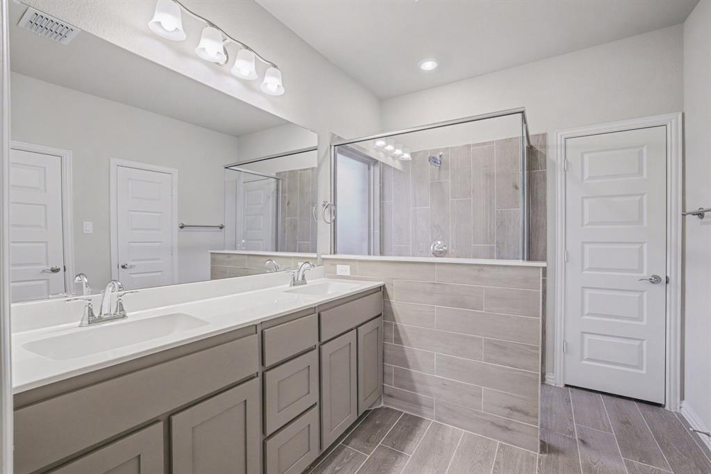 2404 Peebles Lane Denton, TX 76207 - Photo 16 of 30 a bathroom with a double vanity sink a mirror and a shower