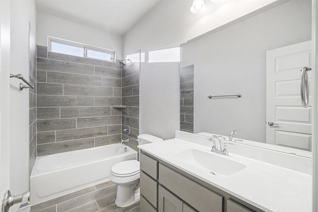 2404 Peebles Lane Denton, TX 76207 - Photo 20 of 30 a bathroom with a bathtub shower sink vanity mirror and toilet