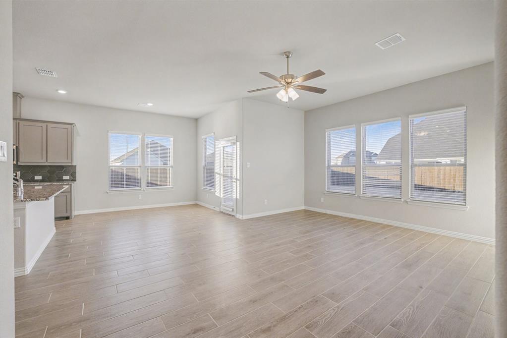 2404 Peebles Lane Denton, TX 76207 - Photo 6 of 30 a view of an empty room with a kitchen and wooden floor