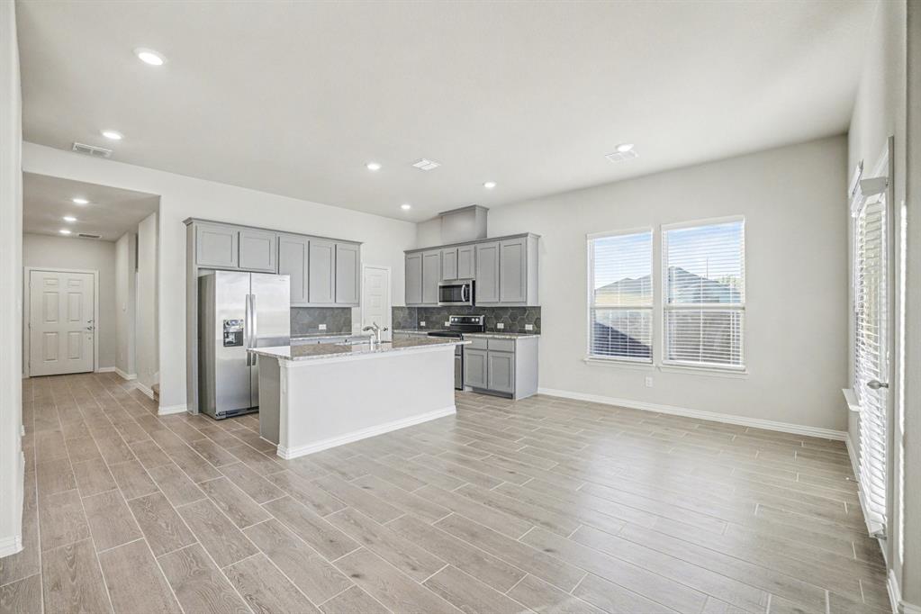 2404 Peebles Lane Denton, TX 76207 - Photo 9 of 30 a view of a kitchen with refrigerator microwave and wooden floor