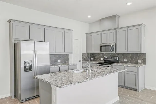 a kitchen with stainless steel appliances granite countertop a refrigerator sink stove microwave and cabinets