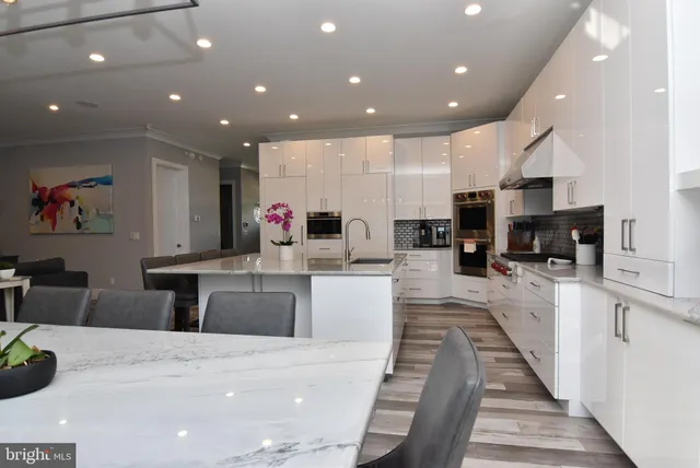 a large kitchen with stainless steel appliances kitchen island granite countertop a large counter top a stove a sink a dining table chairs and view kitchen