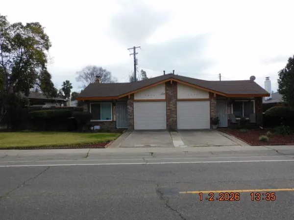 a front view of a house with a garden and trees