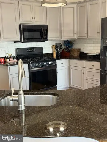 a kitchen with stainless steel appliances granite countertop a refrigerator a stove and a sink