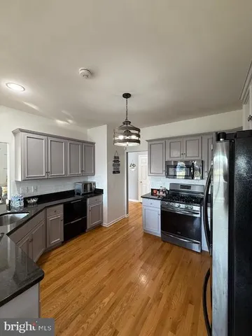 a kitchen with stainless steel appliances granite countertop a sink a stove top oven a counter space and cabinets