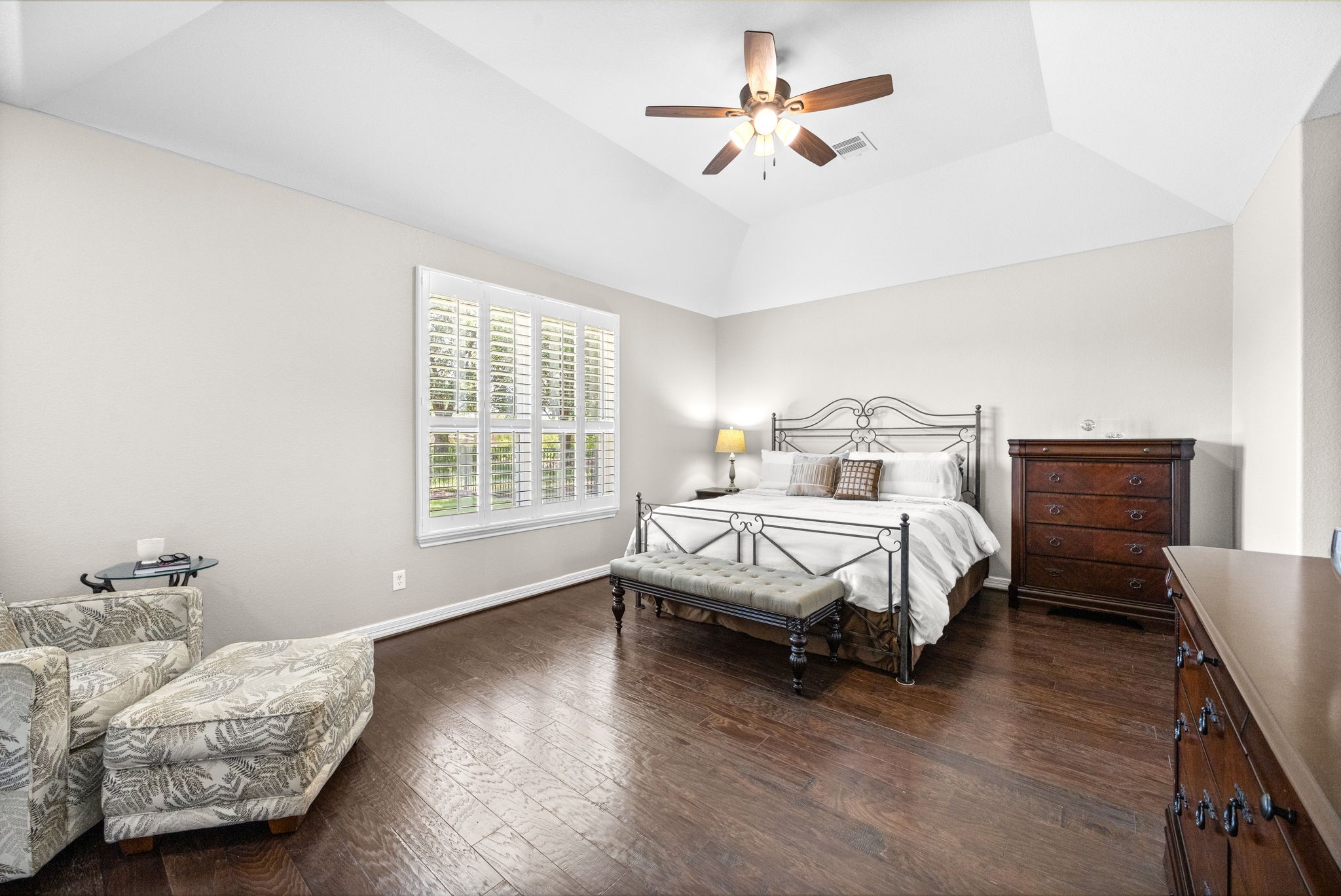 27642 Linden Ridge Lane Fulshear, TX 77441 - Photo 17 of 42 The private Primary Suite is tucked away at the back of the home for maximum peace and privacy. Plantation shutters adorn the windows, while soaring 11-foot ceilings and rich wood flooring create an elegant and relaxing retreat. The spacious layout easily accommodates large furniture and offers plenty of room for a cozy sitting area, making it the perfect place to unwind at the end of the day.