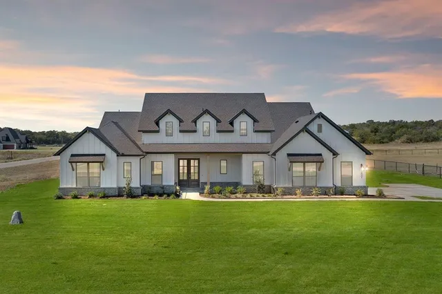 a front view of a house with a garden and trees