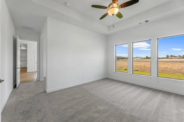 a view of an empty room with window and a kitchen