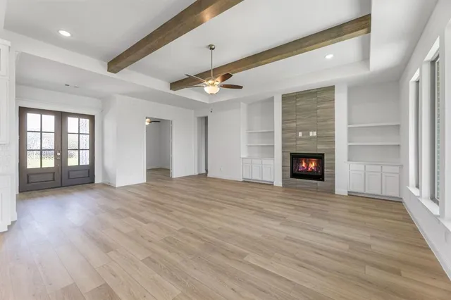 an empty room with wooden floor fireplace and windows