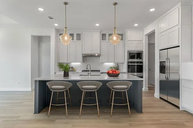 a kitchen with granite countertop stainless steel appliances a table and chairs in it