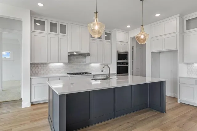 a kitchen with a sink center island cabinets and stainless steel appliances
