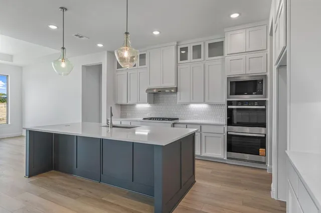 a kitchen with kitchen island a sink stainless steel appliances and cabinets
