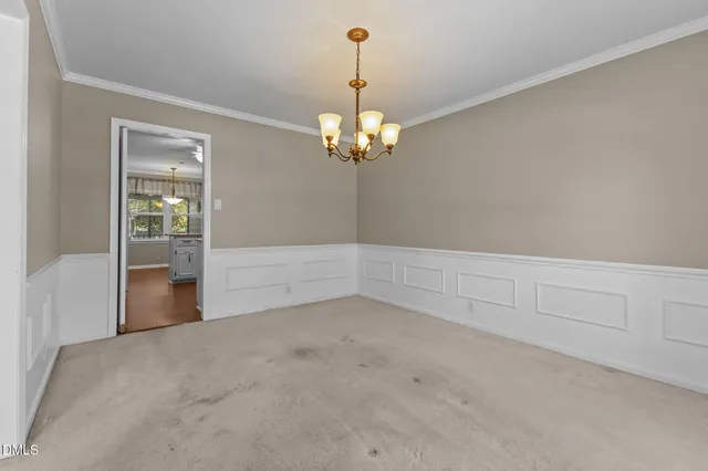 an empty room with chandelier fan and windows