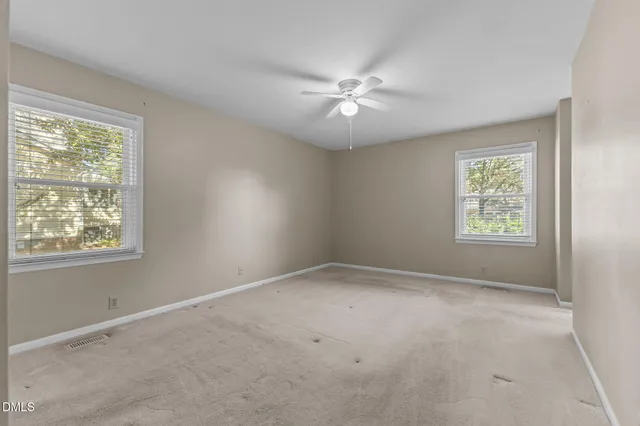 an empty room with fan and windows