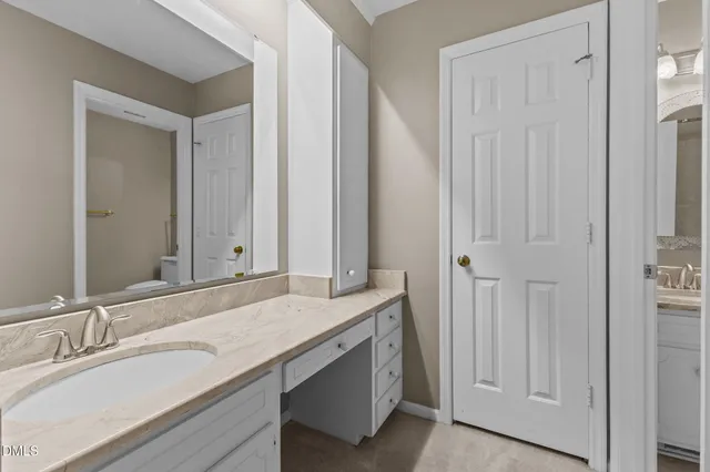 a bathroom with a granite countertop toilet a sink and a mirror