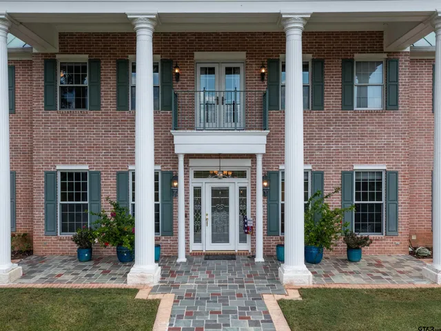 a view of a brick house with potted plants and large windows