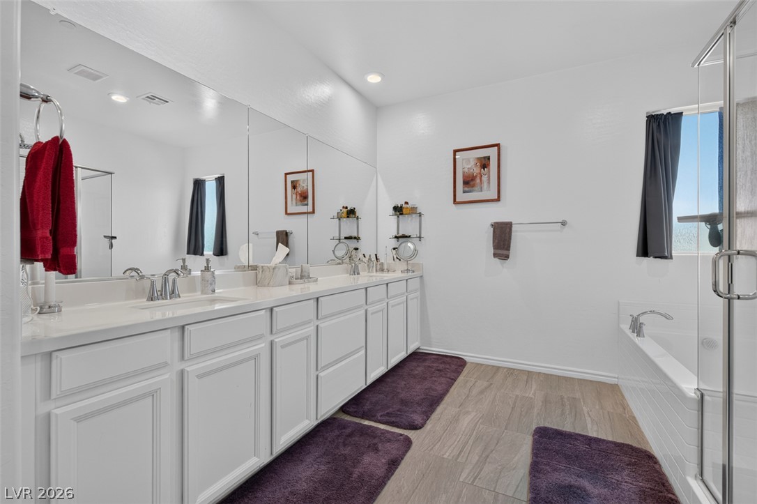 1824 Redland Ridge Street Henderson, NV 89002 - Photo 41 of 69 A well-lit primary bathroom featuring a double vanity, tile flooring, and a spacious tub and shower combination.