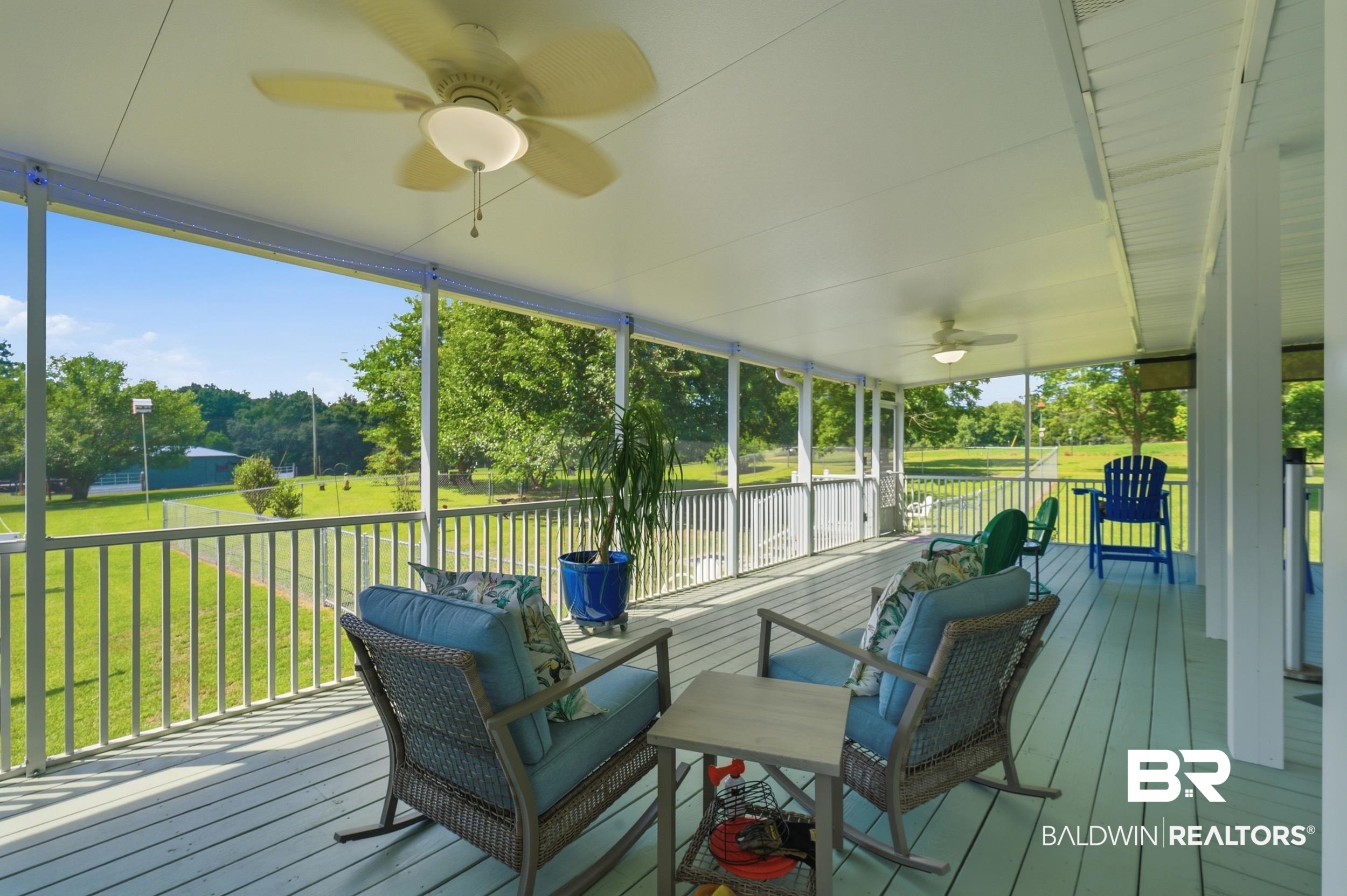 15855 Calvin Richerson Road Bay Minette, AL 36507 - Photo 17 of 83 Expansive screened porch featuring a light-toned wood deck, multiple ceiling fans with integrated lighting, and white railings overlooking a generous lawn with mature trees