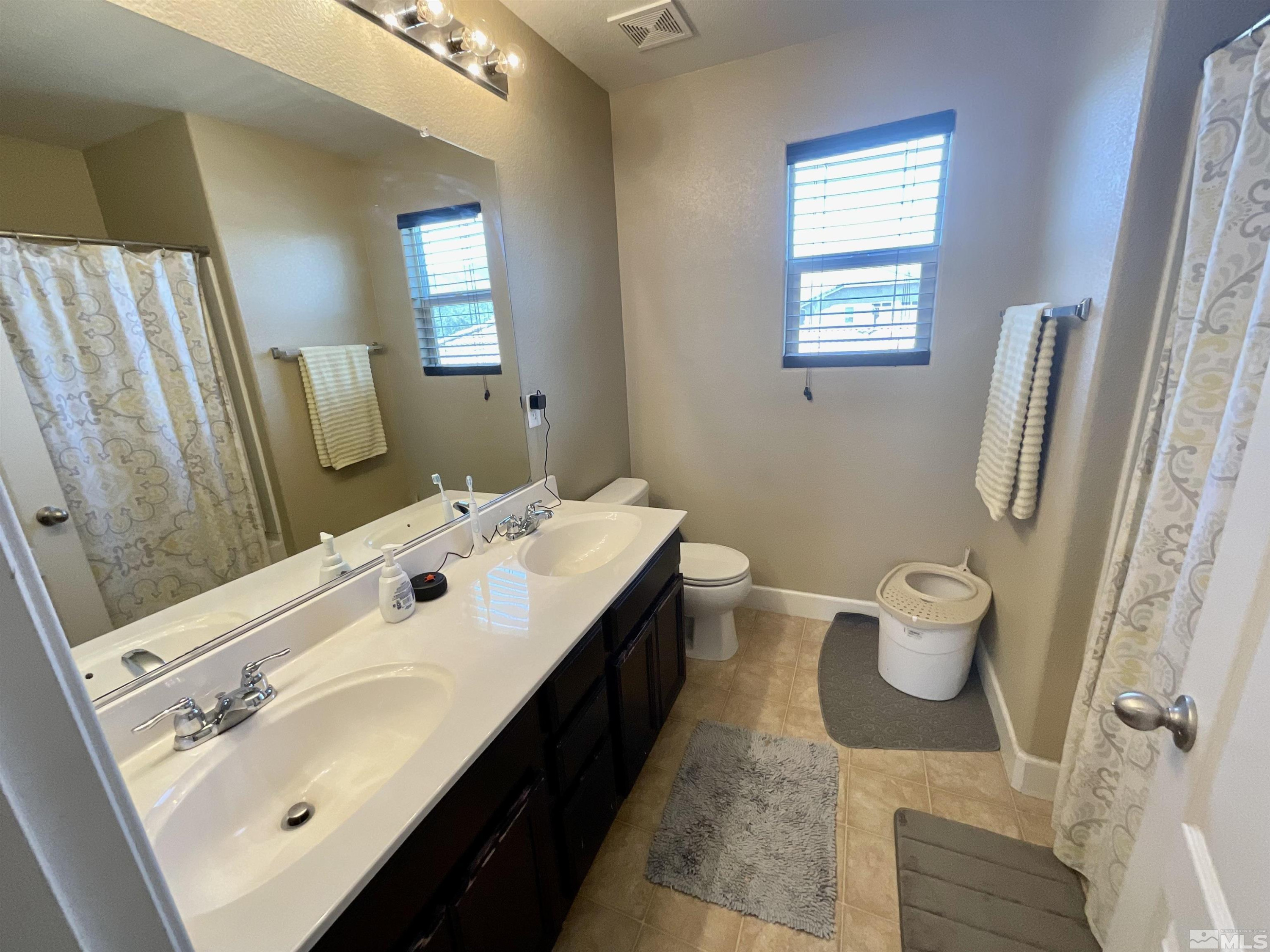 11640 Cervino Drive Reno, NV 89521 - Photo 15 of 26 a bathroom with a double vanity sink toilet and a mirror