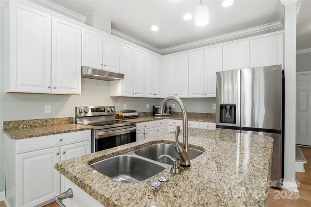 a kitchen with granite countertop a sink a refrigerator and cabinets