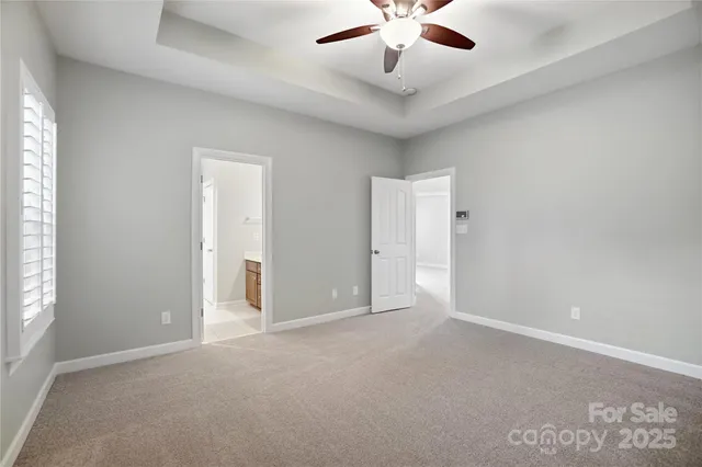 an empty room with chandelier fan and windows