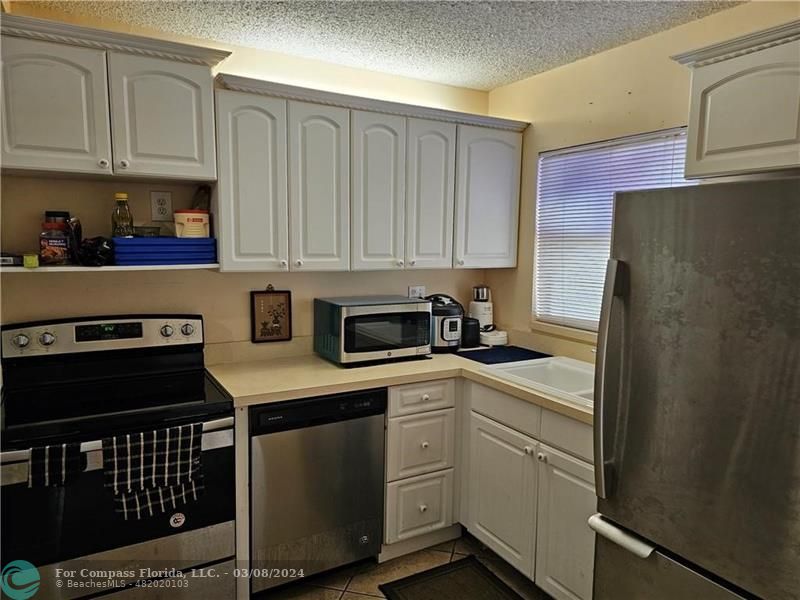 a kitchen with stainless steel appliances granite countertop a refrigerator stove sink and cabinets