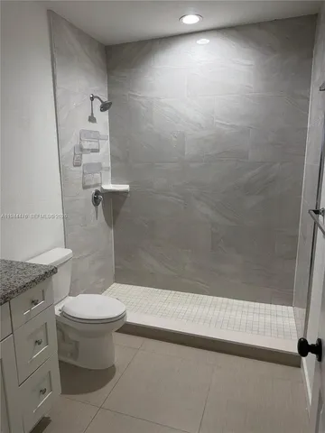 a bathroom with a granite countertop toilet a sink and a shower