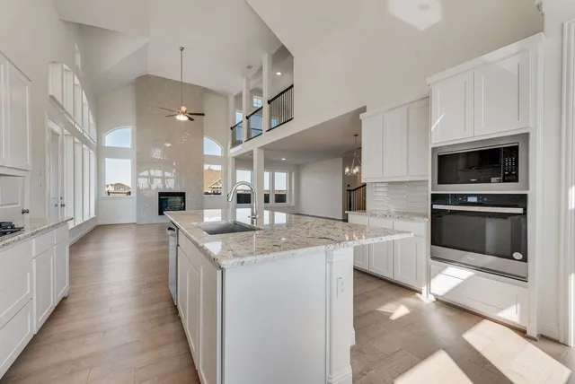 a large kitchen with stainless steel appliances granite countertop a lot of counter space and wooden floors