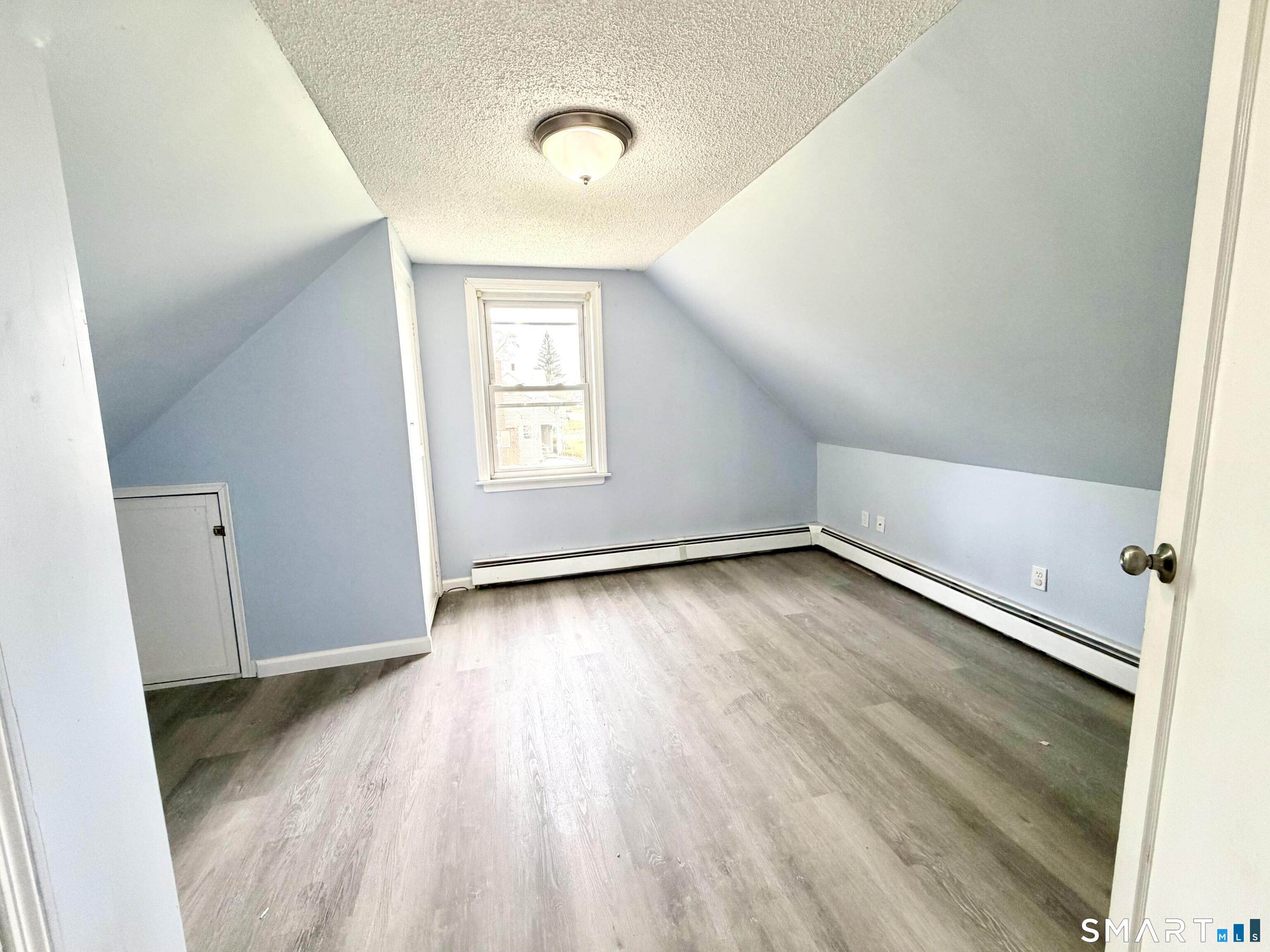 102 Benham Street Bristol, CT 06010 - Photo 13 of 17 an empty room with wooden floor and windows