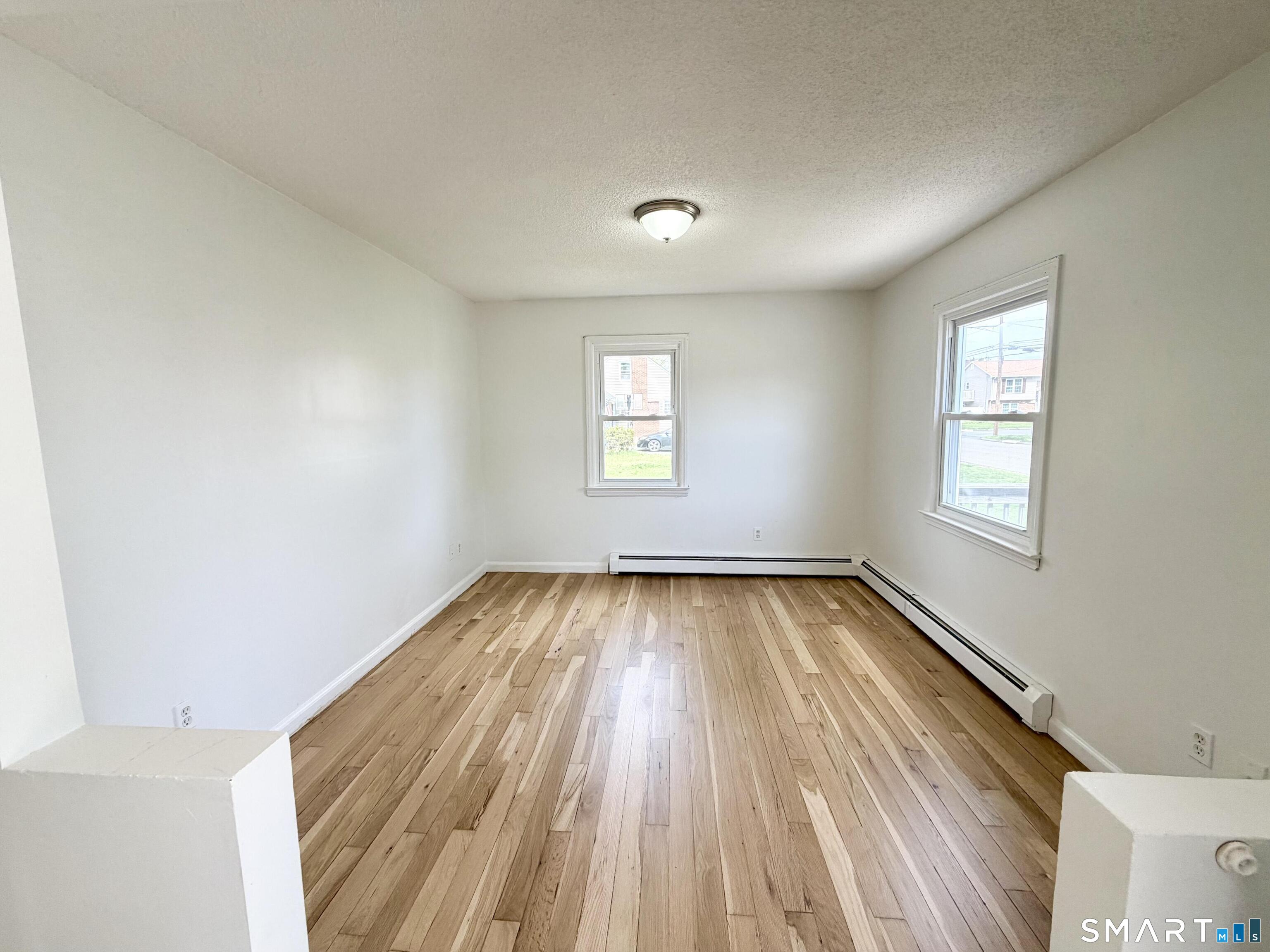 102 Benham Street Bristol, CT 06010 - Photo 10 of 17 an empty room with wooden floor and windows