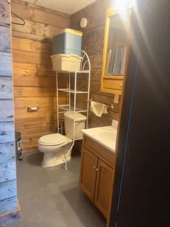 a bathroom with a granite countertop toilet a sink a mirror and shower