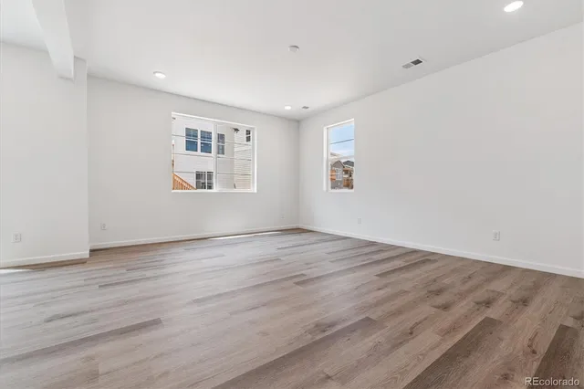 an empty room with wooden floor and windows