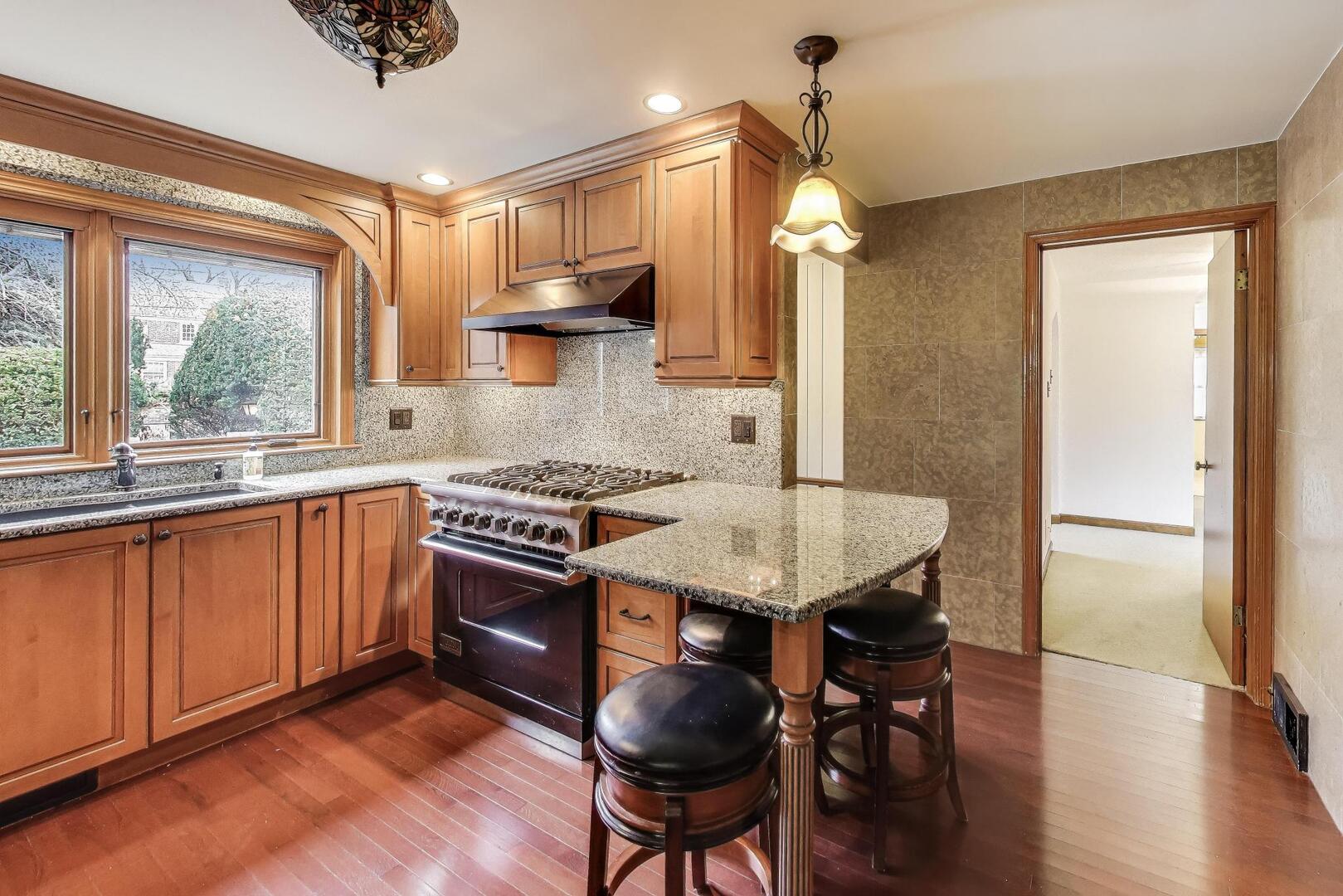 1115 North Ridgeland Avenue Oak Park, IL 60302 - Photo 9 of 40 a kitchen with stainless steel appliances granite countertop a stove a refrigerator a sink dishwasher a dining table and chairs with wooden floor