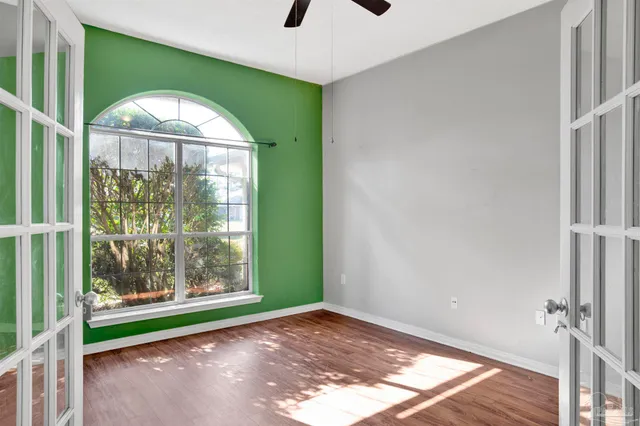a view of empty room with wooden floor and fan