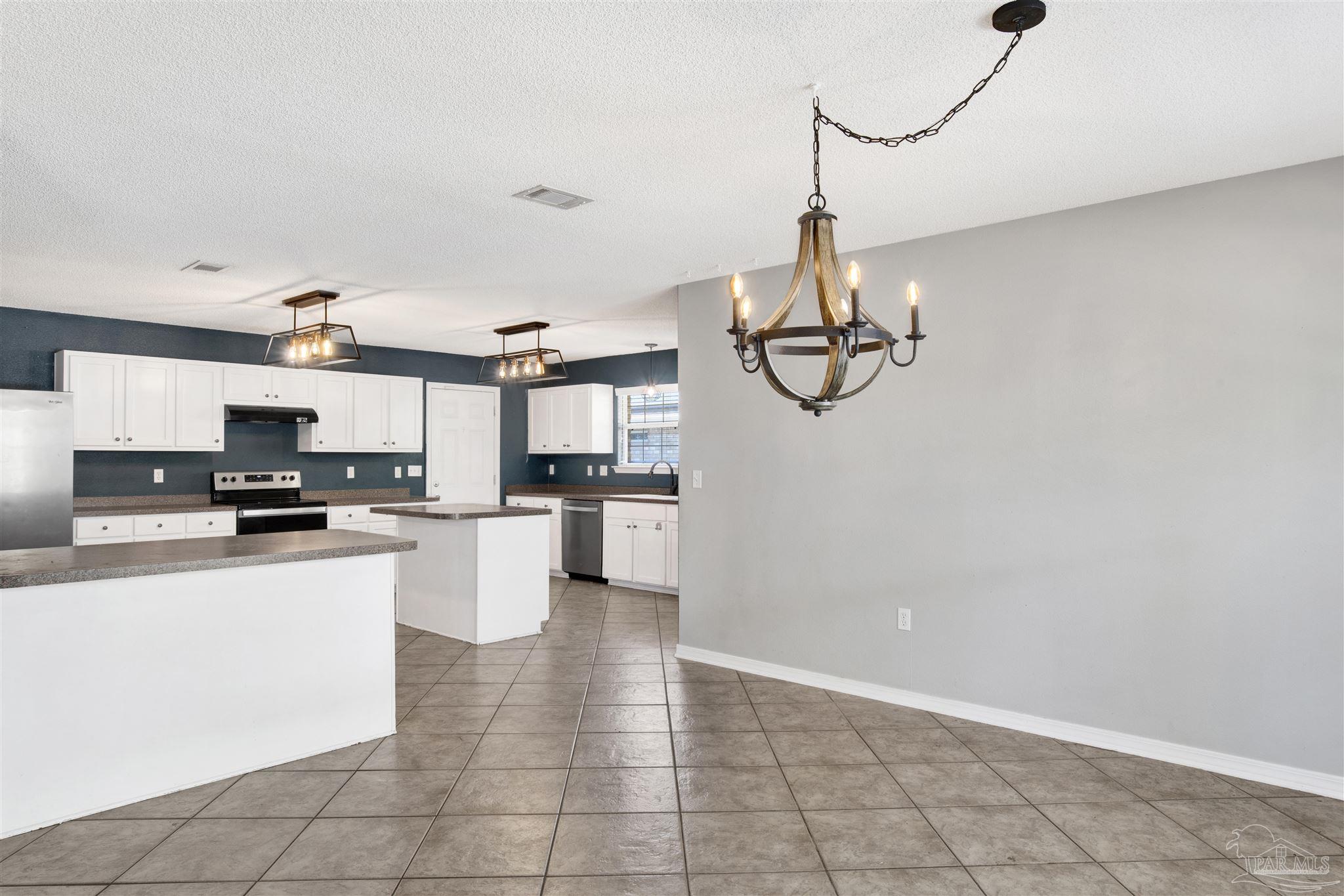 7604 Brewster Street Navarre, FL 32566 - Photo 16 of 36 a kitchen with stainless steel appliances granite countertop a sink a stove top oven a counter space and cabinets